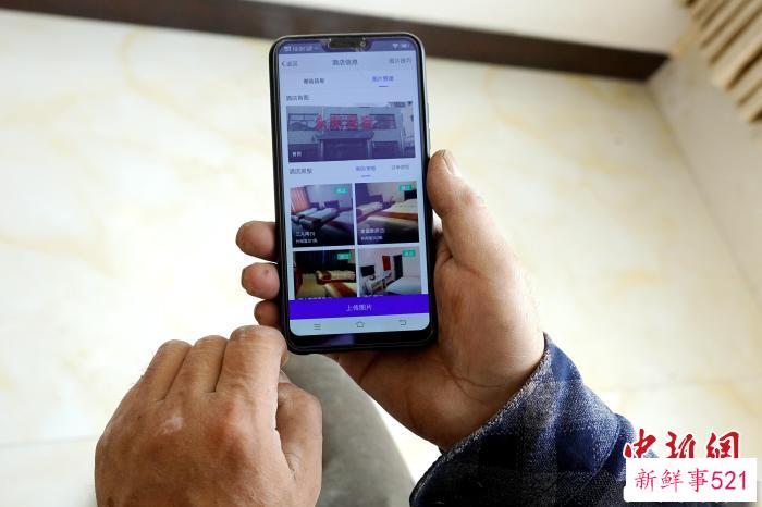 图为村民展示自家民宿在旅游平台等待订单。　马铭言 摄