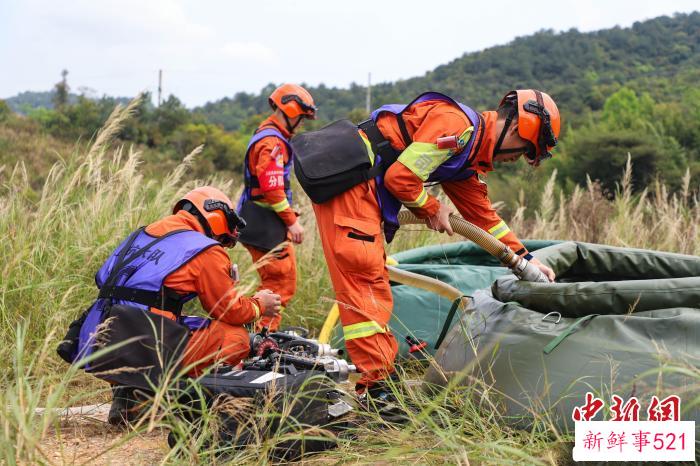 以水灭火中，消防员正在架设水泵。　温伟强 摄