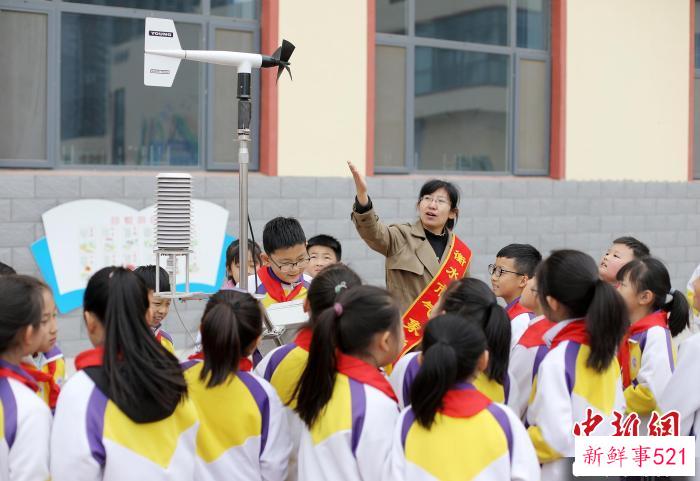 气象科普人员为学生展示、讲解便携式自动气象站。　陈康 摄