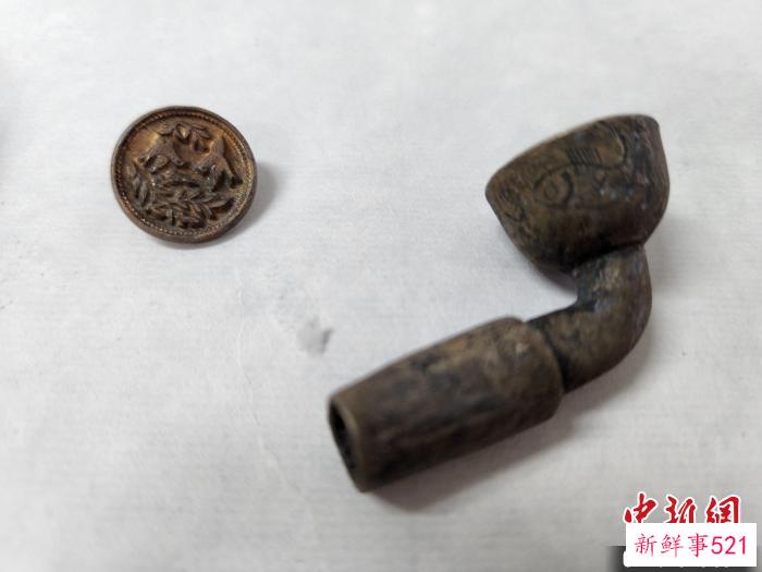 带图案的金色纽扣、刻有鱼纹的烟斗。　赵晓 摄