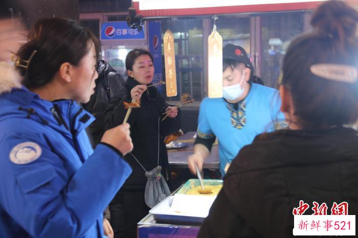 游客们围着小摊吃烤羊肠。　潘琦 摄