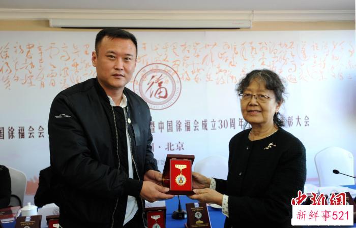 中国郭沫若研究会名誉会长、中国徐福会名誉会长郭平英(右)为中国徐福会常务理事徐云龙颁发奖章。　王德成 摄