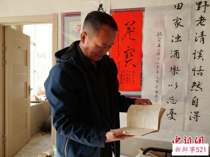 图为郭成翻看父亲的笔记。　胡立忠 摄
