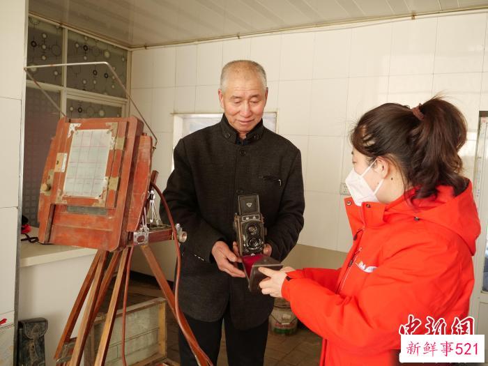图为程森林(左)展示老相机。　胡建华 摄