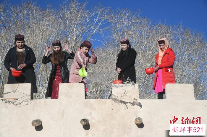 图为村庄里的女性正在房屋顶上洒水。　孙亭文 摄