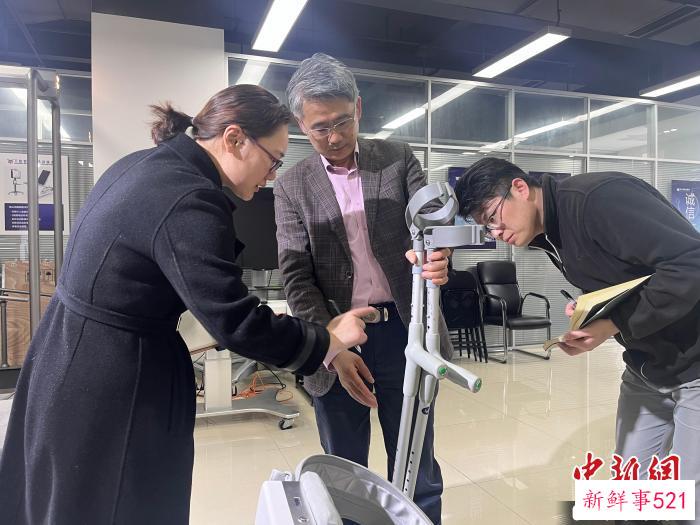 电子科技大学教授程洪(左二)就外骨骼机器人穿戴舒适度进行探讨。　王利文 摄