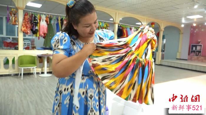 排丽旦·吐地展示“古丽娃娃”礼盒中用艾德莱斯绸制作的小裙子。　左丹丹 摄