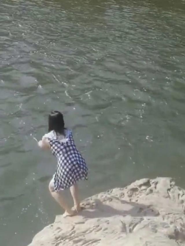 女子不惧危险,不戴游泳用具,仅穿着裙子,就跳入水流端急的河中